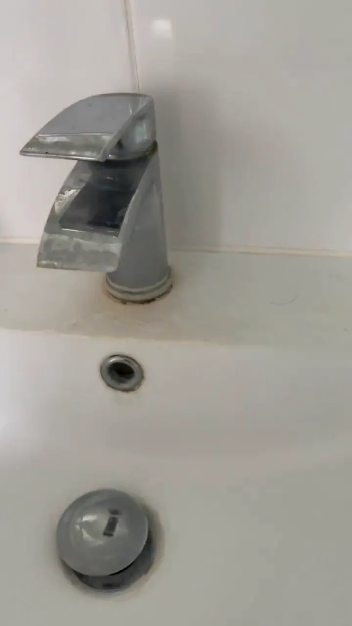 Chrome basin tap with limescale build-up around the base