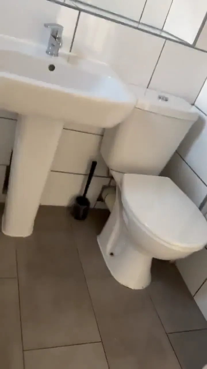 The same white-tiled bathroom with a clean basin and toilet