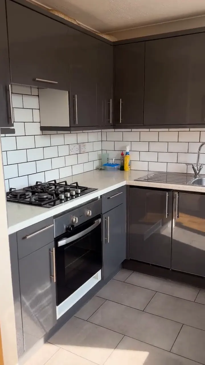 The same kitchen with grey gloss units, clean worktops and a clear tiled floor