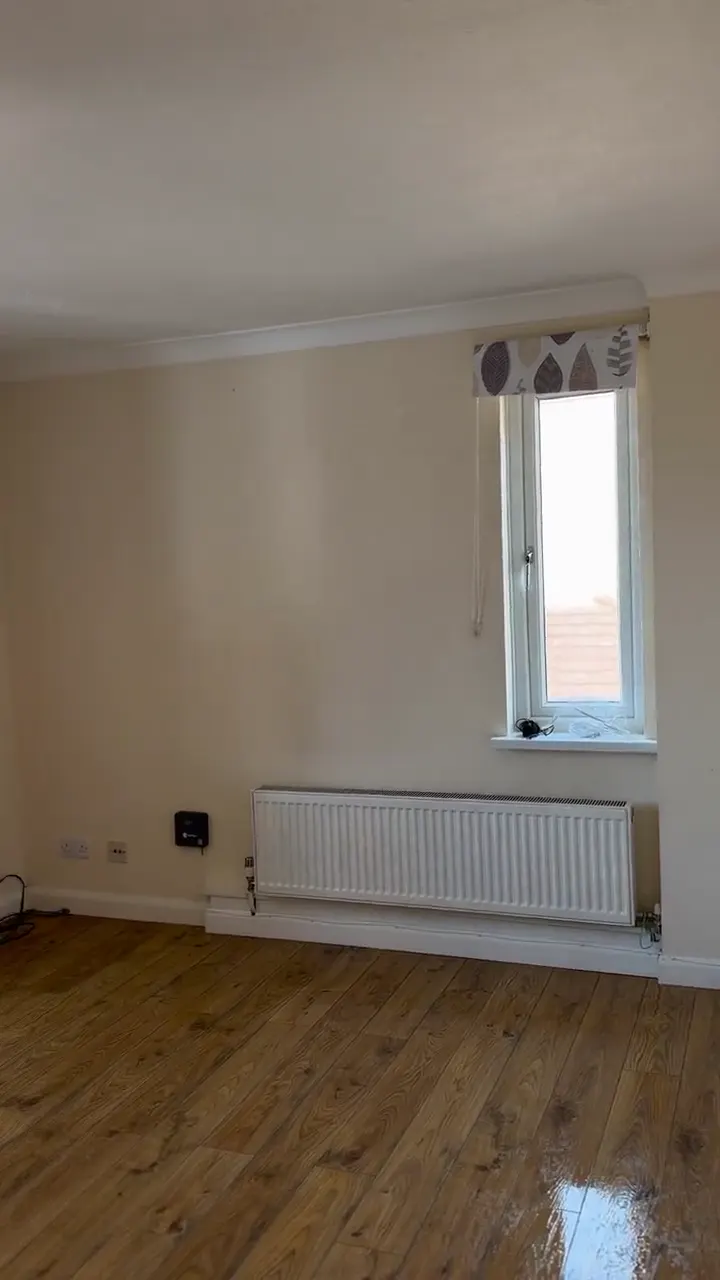 The same room with a leaf-pattern blind, now empty with a clean wooden floor